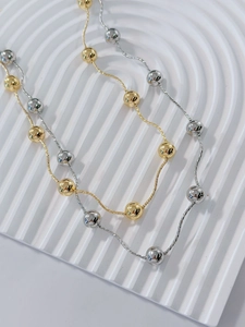 Close-up of 18k gold and silver beads on a delicate chain with a high-polished finish