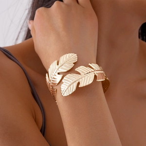 Detailed view of the intricate golden feather texture on the adjustable cuff bracelet