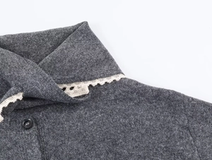 Detail of dark grey knit cardigan showing navy collar with white lace trim and button