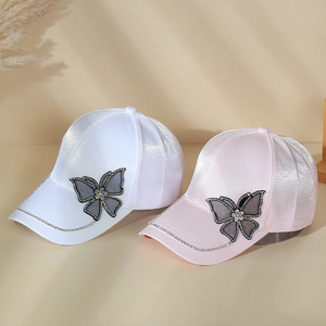 Close-up of satin baseball caps featuring large crystal-trimmed butterfly decorations