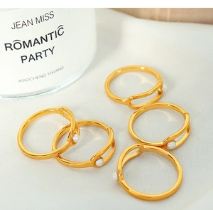 Detail of five adjustable gold rings featuring elegant white pearls on a soft fabric base
