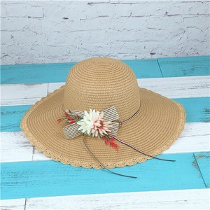Detail eines breiten Strohhutes mit Wellenrand und dekorativem Blumenband für Damen