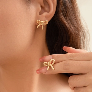 Close-up of golden bow-shaped stud earrings with polished metal finish on ear