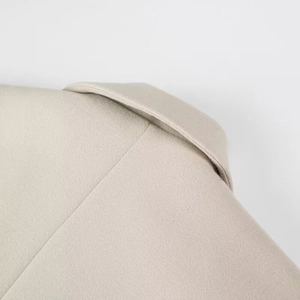 Gros plan détaillé des coutures sur le tissu en laine beige au col et à l'épaule
