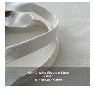 Close-up of durable wide woven shoulder strap on minimalist white corduroy bucket bag