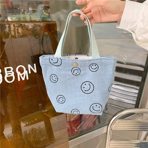 Sky blue corduroy mini tote bag with black embroidered smiley faces and snap button