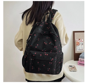 Corduroy cherry backpack for women shown worn on back in a cozy home setting