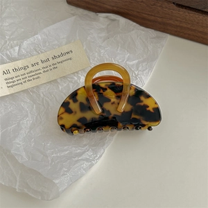 Detailed view of an amber tortoise shell hair claw clip with a top handle design