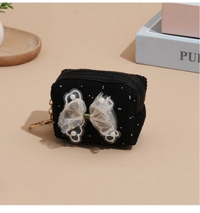 Close-up of black corduroy coin purse with lace bow, pearls and golden keychain