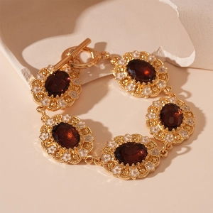 Macro detail of vintage gold bracelet with red stones and white enamel floral accents