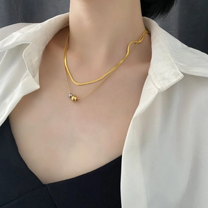 Elegant double-layered gold chain necklace with gold and silver ball pendants on a model