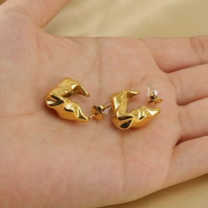 Unregelmäßige Ohrringe aus 18K vergoldetem Edelstahl auf goldenem Seidenstoff Hintergrund