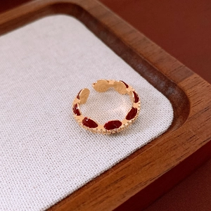 Detail of gold-plated open ring with red enamel teardrop and sparkling zircon accents