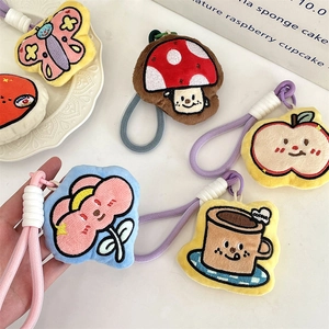 Detailed view of colorful plush charms with embroidery and braided lanyards on a plate