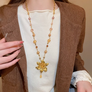 Détail d'un collier vintage avec pendentif fleur dorée et perles élégantes colorées