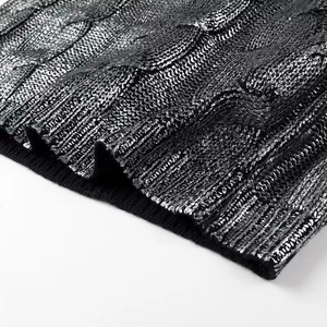 Gros plan sur un pull en maille torsadée noire avec revêtement argenté et détails côtelés