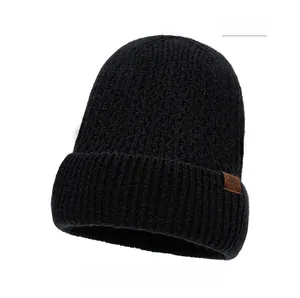 Close-up of black knitted beanie featuring a brown leather snowflake patch and fine texture