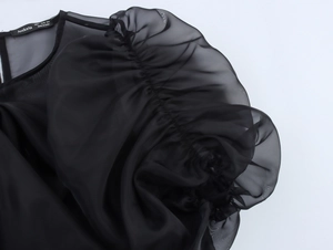Détail du tissu en organza noir avec texture bouffante et étiquette de la marque