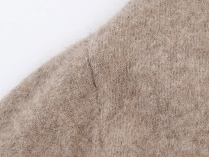 Dettaglio del tessuto a maglia beige morbido con fibre lunghe e trama soffice
