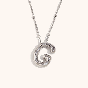 Macro shot of silver puffy letter G balloon pendant with high mirror polish and bead chain