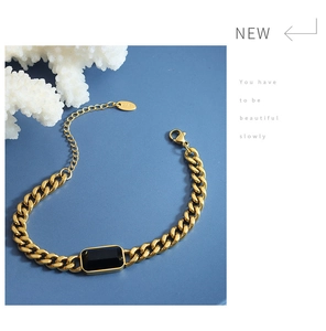 Detailed view of golden Cuban link bracelet with black square stone and lobster clasp