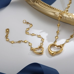 Golden titanium steel jewelry set with heart-shaped necklace and bracelet on blue silk