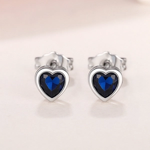 Macro detail of heart-shaped earrings with deep blue gemstones and silver metal finish