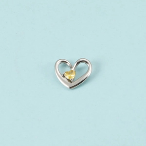Gros plan d'un pendentif cœur en argent serti d'un cristal de pierre de naissance jaune