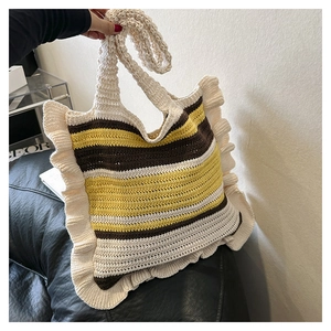 Detail of hand-woven knit tote bag with beige, brown and yellow stripes texture