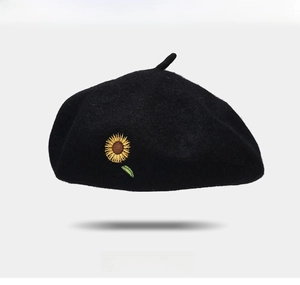 Detailed close-up of yellow sunflower embroidery on a black wool beret with soft fabric