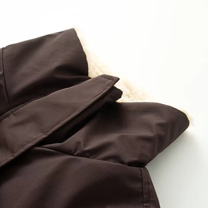 Détail d'un col de veste marron foncé avec doublure épaisse en faux mouton blanc