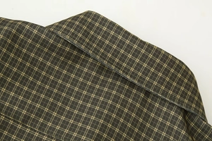 Detailed macro view of the lapel collar and green plaid fabric with precise stitching