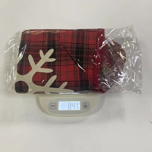 Detail view of a plaid Christmas stocking with white snowflake on an electronic scale