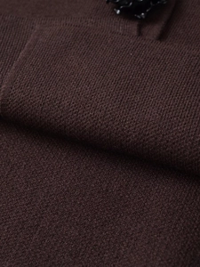 Détail du tissu en maille marron chocolat avec un bouton fleur 3D noir élégant de luxe