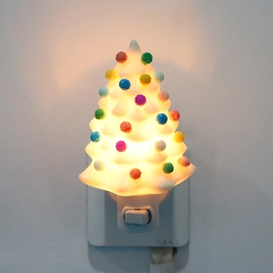 Close-up of a Christmas tree night light with colorful glowing beads on white ceramic