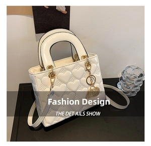Detailed view of a white heart-quilted handbag featuring elegant gold-tone heart charms.