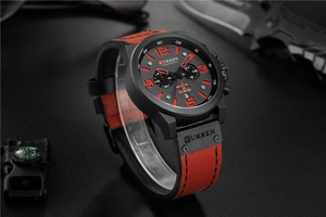 Detail of red leather strap and black dial chronograph watch with calendar display