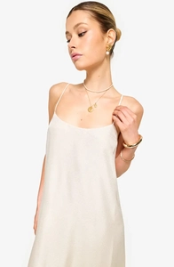 Detail of elegant white summer dress with spaghetti straps and gold jewelry set