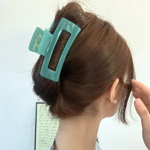 Chic sage green rectangular hollow hair claw clip worn on wavy brown hair