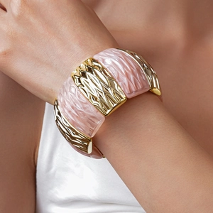 Detail of pink marble acrylic and textured gold-plated metal cuff bangle bracelet