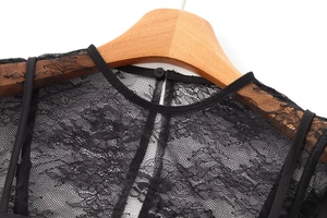 Close-up of black floral lace neckline and shoulder detail on a wooden hanger