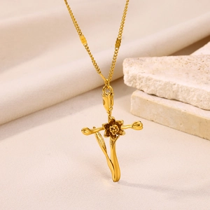 Detail shot of a gold-plated necklace with a floral cross pendant on textured stone
