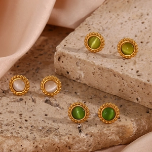Detailed macro view of vintage round gold earrings with colorful cat eye stones on stone