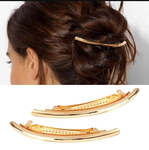 Close-up of sleek gold curved hair clip with polished finish and spring closure