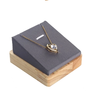 Close-up of heart-shaped gold pendant necklace with white gemstone on wooden display