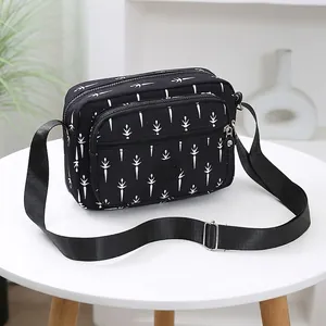 Waterproof nylon crossbody bag with white plant pattern and adjustable strap