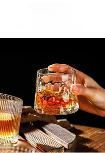 Close-up of hand holding a textured whiskey glass with hammer patterns and amber liquid