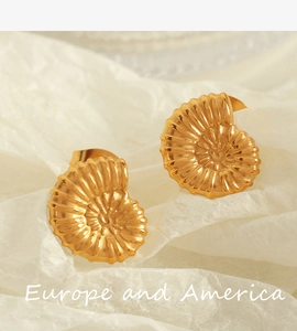 Macro shot of 18K gold plated titanium nautilus shell stud earrings on white paper