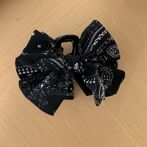 Détail d'une pince à cheveux en tissu imprimé cachemire noir avec un nœud élégant