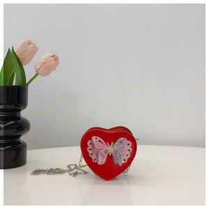 Detail view of heart-shaped crossbody bag with vibrant 3D butterfly and silver chain